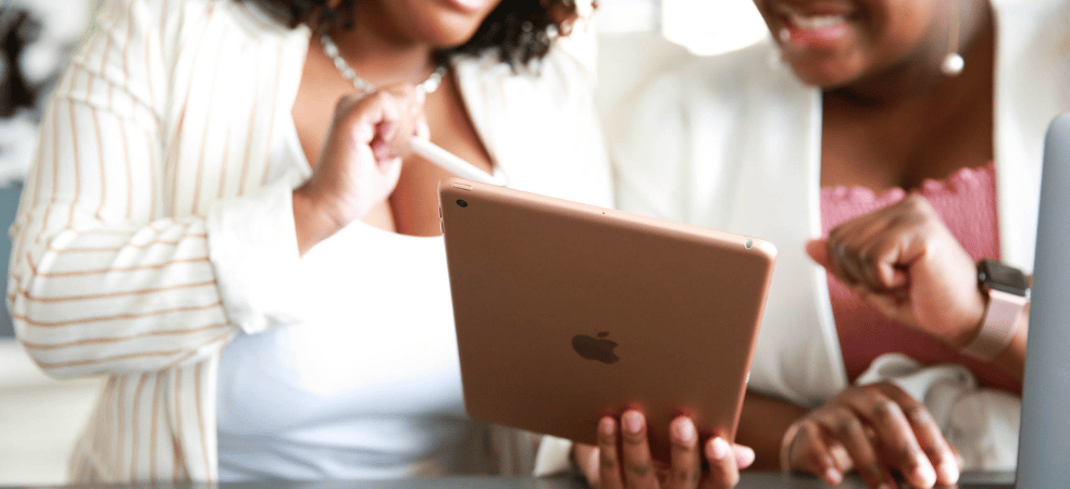Two business owners reviewing website performance and SEO strategy on a tablet and laptop.