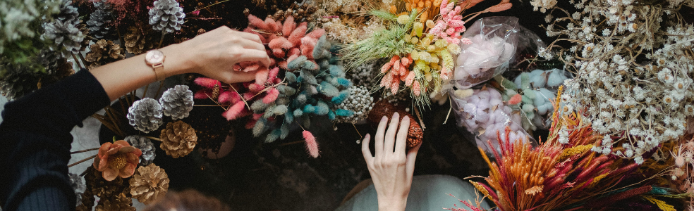 Seasonal floral arrangements and dried flowers displayed in a florist's workspace.