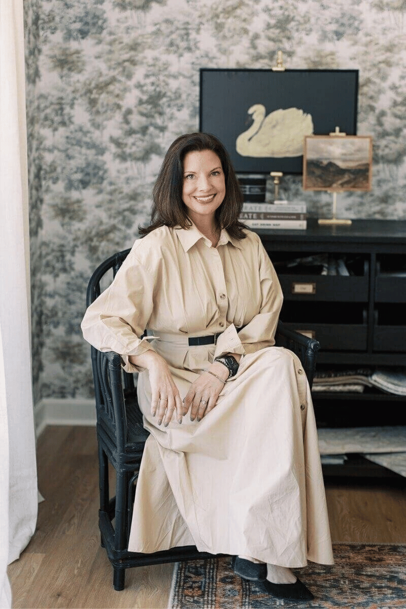 Interior designer Brenna seated in a styled home office with wallpaper, artwork, and neutral decor